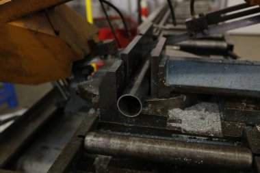 Endüstriyel mengeneye sıkıştırılmış metal boru. Kapalı. Metal talaşlarıyla çevrili yeni kesilmiş tüp görünüyor.