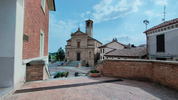 Tuğla çan kulesi Marsciano Umbria İtalya 'daki San Giovanni Kilisesi' nin saat ve heykeli bulutlu mavi gökyüzünün altındaki kaldırımlı bir yoldan görüldü. Yüksek kalite fotoğraf