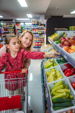 Mutlu anne ve kız marketten sağlıklı ürünler alıyor.