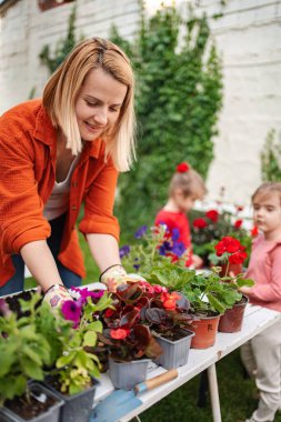 Çocuklar bahçeyle uğraşırken kadınlar canlı çiçeklerle ilgilenir..