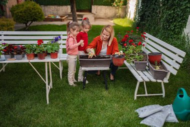 Büyüleyici bir bahçede birlikte çiçek dikiyorlar.