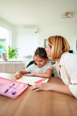 Anne kızına evde ödevlerinde nazikçe yardım ediyor..