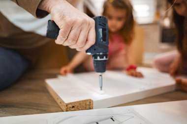 Eller, iki çocuk hevesle gözlemlerken ve uğraşırken bir projeyi birleştirmek için bir tatbikat yapmakla meşgul. Sıcak ortam, bu samimi aile aktivitesinde yaratıcılığa ve takım çalışmasına ilham veriyor..