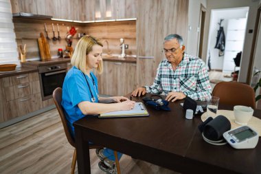 Hemşire yaşlı bir adam için sağlık değerlendirmesi yapıyor..