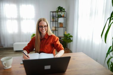 Bir kadının masasında yazmaktan hoşlandığı gibi parlak bir oda bitkilerle dolu..