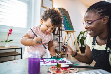 Genç bir çocuk neşeyle resim yapar rehberlik ve kahkaha ile.