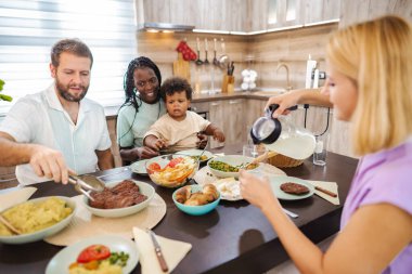 Masanın etrafında toplanan bir aile lezzetli yemekler ve kahkahalar paylaşıyor..