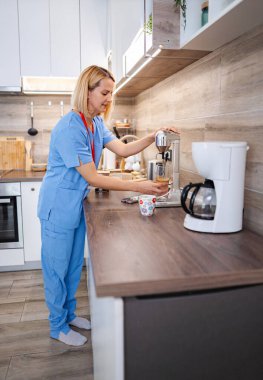 Mutfakta kahve yapan kadın bir tıp uzmanı.