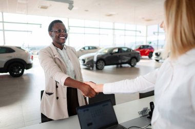 Başarılı bir araba satın alma deneyimini el sıkışarak tamamlayan iki kadın.