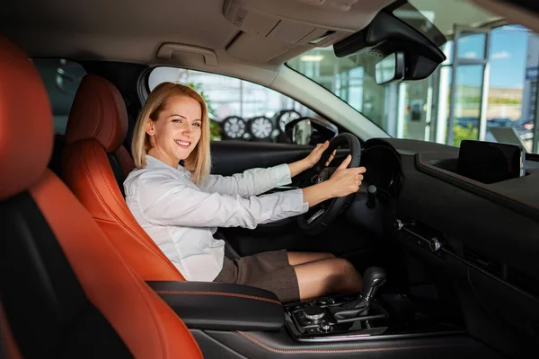 Test sürüşü sırasında gülümseyen ya da deri koltuklu yeni bir araba alan bir kadın.