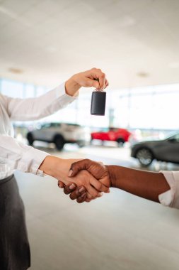 People shaking hands and exchanging car keys in a dealership setting