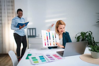 Diverse female designers collaborating on creative project using color swatches