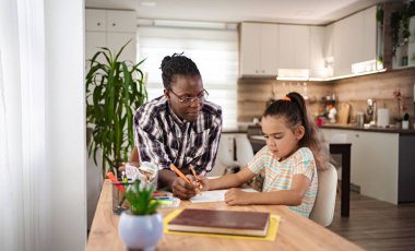 Öğretmen ve çocuk sıcak, davetkar bir mutfakta ev ödevlerine birlikte odaklanırlar..