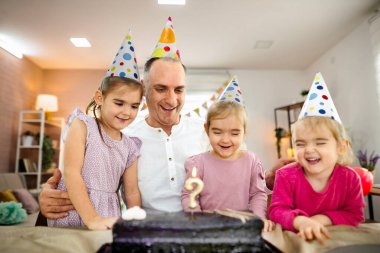 Bir baba, mutlu kızlarıyla birlikte doğum gününü kutlar..