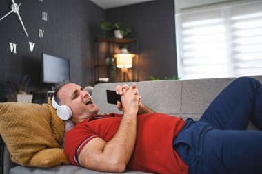 Mutlu adam evde kulaklıkla müzik dinlerken şarkı söylüyor..