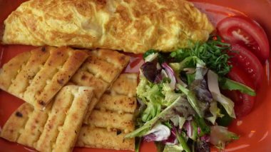 Taze omlet, salata, domates ve kızarmış pide ile sağlıklı kahvaltı tabağı.