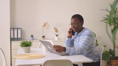 Profesyonel bir kadın telefon görüşmesi yapıyor ve evinde dizüstü bilgisayar kullanıyor.