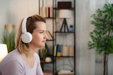 Evde dinlenen, kablosuz kulaklık kullanan bir kadın.