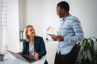 İki iş kadını bir dizüstü bilgisayar ve dijital tablet kullanırken işi tartışıyor