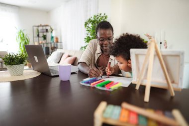 Anne ve çocuk bir masada çizim yapıyor, yaratıcılığın ve bağlanma zamanının tadını çıkarıyor.