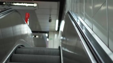 Bulanık insanlarla dolu metro istasyonuna inen boş bir yürüyen merdivenden çekilen görüntüler.