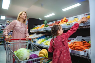 Anne ve kızı markette birlikte taze ürün alışverişi yapıyorlar.
