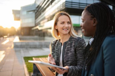 Çeşitli iş kadınları dışarıda dijital tabletle teknolojiyi tartışıyor