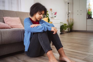 Evde elinde elektronik sigara tutan üzgün genç bir kadın bağımlılık fotoğrafı üzerinde kafa yoruyor.