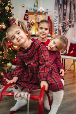 Üç küçük kız Noel 'i evde kutluyor, tatilin tadını çıkarıyor.