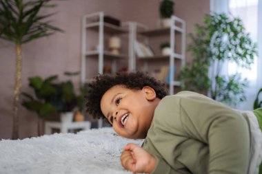 Küçük çocuk kıkırdıyor, eğleniyor ve evde rahat anlar yaşıyor.