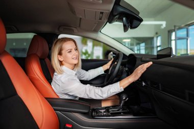 Şov salonundaki modern arabanın özelliklerini ve göstergelerini karşılaştıran bir kadın.