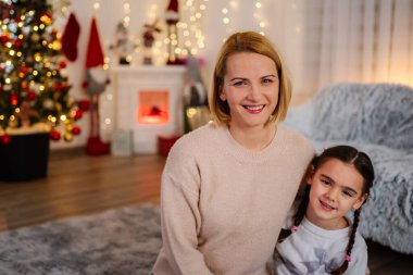 Anne ve kızı gülümsüyor, özel aile zamanlarının tadını çıkarıyor.