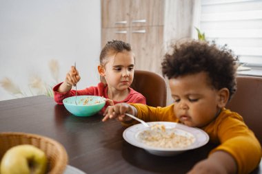 Masada iki çocuk şakacı ifadelerle yemek yiyor..