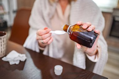 Bir insan evde otururken ilaçlarını daha iyi hissetmek için dikkatlice ölçer..