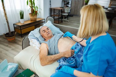 Bakıcı, evdeki yaşlı bir adamın sağlığını değerlendirir..