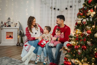 Mutlu bir aile Noel arifesini ağaç ve şöminenin yanında birlikte geçirir.