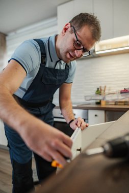 Yeni mutfak dolapları kuran adam, titizlikle mükemmel bir uyum için ölçüm yapıyor.