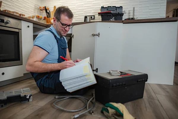 Üniformalı bir adam evinin tadilatı sırasında not defterine yazıyor.