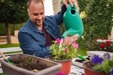 İnsanoğlu renkli çiçekleri canlı bahçe boşluğunda sular..