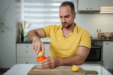 Sağlıklı bir içecek için limon sıkan adam.