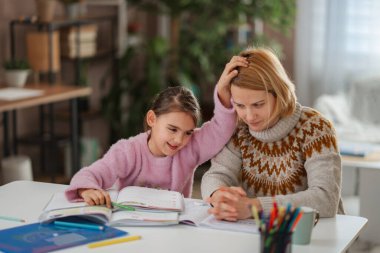 Ev ödevi yaparken kızıyla boğuşan bitkin bir anne.