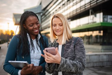 Modern bir şehir ortamında çeşitli iş kadınları cep telefonu ve tablet üzerinden bilgi paylaşıyor
