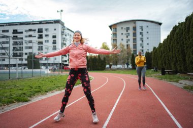 Koşu pistinde birlikte çalışan iki farklı genç kadın.