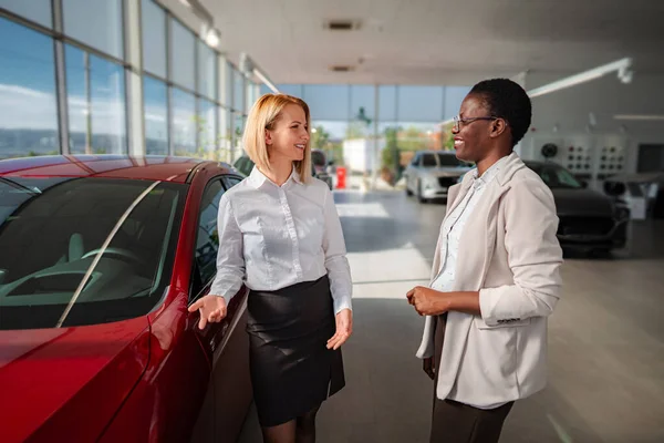 Modern otomobil mağazasında çeşitli kadınlar yeni araba özelliklerini tartışıyor