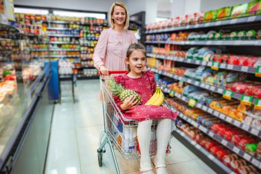Anne ve kızı süpermarket koridorunda alışveriş yaparken eğleniyorlar.