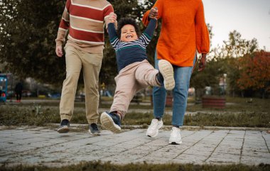 Mutlu bir aile birlikte parkta vakit geçirir, sonbahar havasının tadını çıkarır.