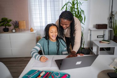 Anne, mutlu kıza ödevlerinde yardım ediyor.