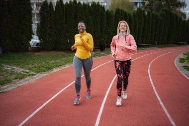 Açık havada koşan iki farklı kadın spor yapıyor.