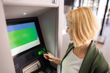 Bir kadın para transferi için ATM 'ye kredi kartı sokuyor.