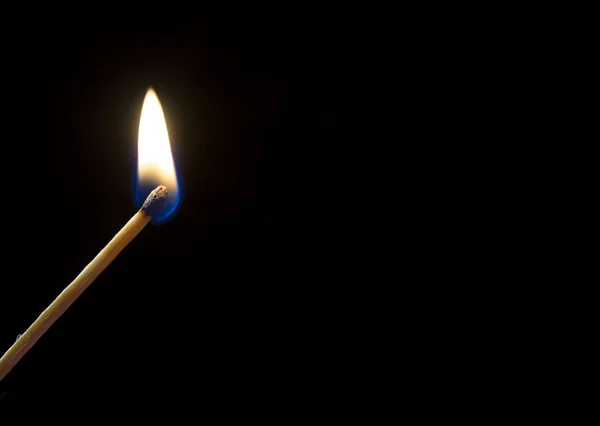 Um fósforo em chamas. Uma foto de perto, um fundo escuro — Fotografia de Stock